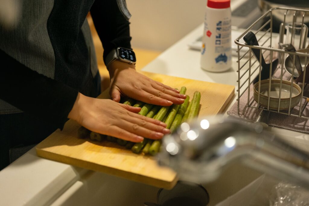 Close-up of hands arranging asparagus on a cutting board in a modern kitchen setting.